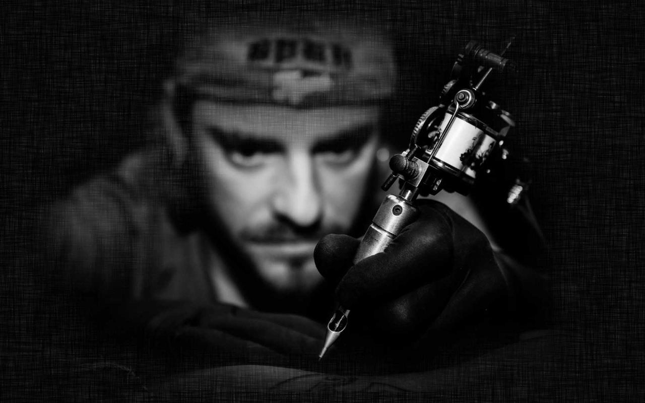 Oliver Sasin blickt konzentriert mit Tattoomaschine in der Hand