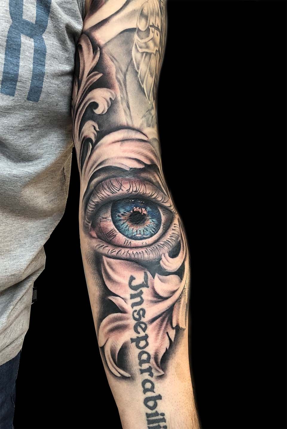 Realistisches Auge mit Ornamenten und Schriftzug am Unterarm