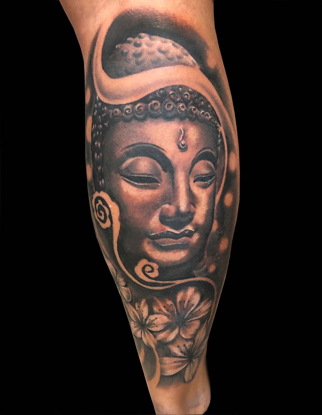 Buddha-Kopf mit Blüten am Unterschenkel