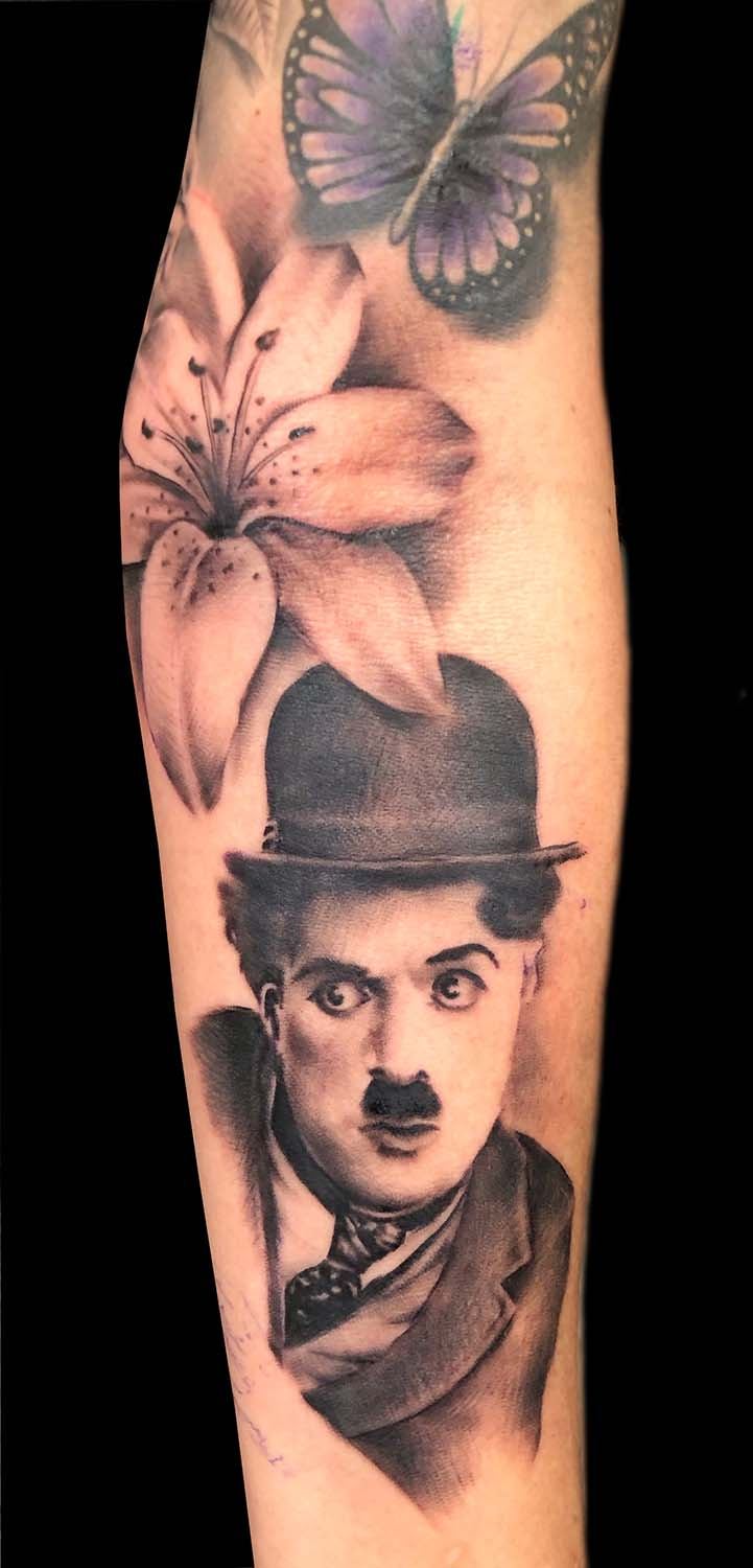 Charlie Chaplin mit Lilie und Schmetterling am Unterarm